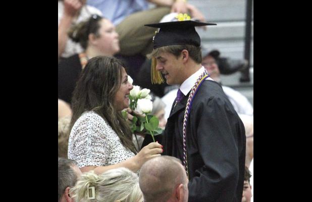 Brek Wiese presents a flower and a long hug to his mother Michelle, as the graduates honor their family and friends during Sunday’s commencement ceremony in Wood River. (—photo by Steve Glenn)