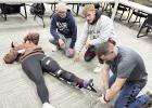 Preston Kuskie (kneeling, left), Ikaiah Edgren (center), and Dakota Green (right), practice applying a traction splint to fellow EMT class participant Sidney Frear. (–courtesy photo) Preston Kuskie (kneeling, left), Ikaiah Edgren (center), and Dakota Green (right), practice applying a traction splint to fellow EMT class participant Sidney Frear. (–courtesy photo)